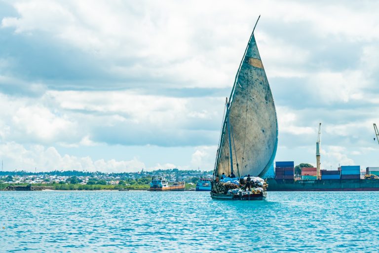 Traditionellt segelfartyg lastat med timmer på väg in mot hamnen i Stone Town